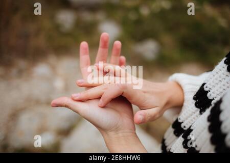Crop anonymous female tourist in knitted sweater with ornament showing friendship gesture on mountain in daylight Stock Photo