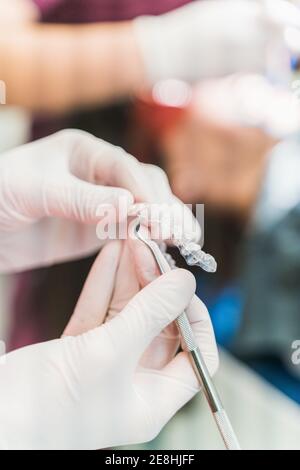 Crop unrecognizable dentist in latex gloves holding ultra thin veneers and scaler while working in dental clinic Stock Photo