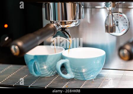 Professional coffee machine pouring coffee into small ceramic cups in coffeehouse with contemporary equipment Stock Photo
