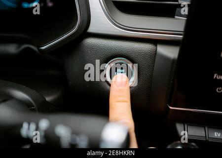 Closeup of crop anonymous male pressing Start Engine Stop button while sitting in modern car before driving Stock Photo