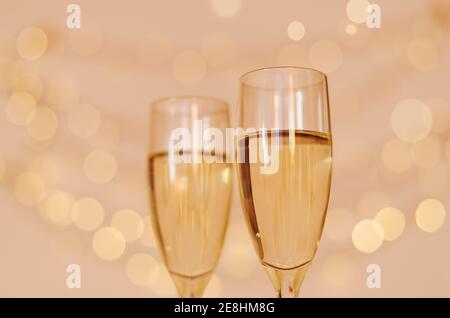Glasses of champagne on glass table with bokeh background close up. New Year, Christmas mood. Greeting card. Party and holiday celebration concept. Stock Photo