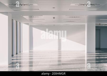 Interior of empty spacious loft hallway with geometrical shadows and sunlight on white walls Stock Photo