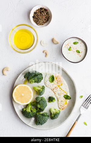 Top view of tasty broccoli with fresh lemon and sauce near bowls with olive oil and spice mix on table Stock Photo