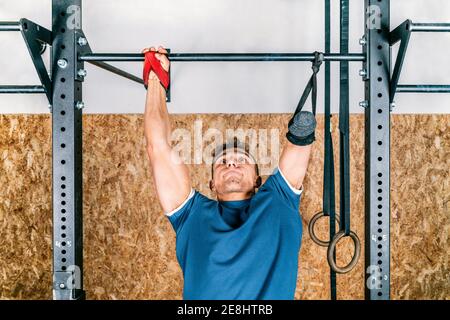 Young athlete handicapped sportsman training on horizontal bar during training in gym Stock Photo