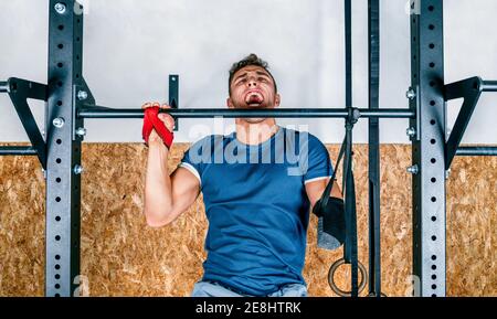 Young athlete handicapped sportsman training on horizontal bar during training in gym Stock Photo