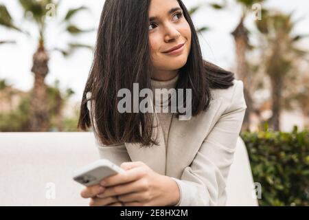 Female entrepreneur using smartphone in street while checking messages in email Stock Photo