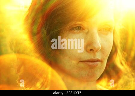 Crop thoughtful adult female resting in nature and looking away pensively under bright sunlight during golden hour Stock Photo