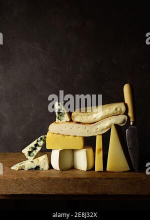 Various cut cheese on wooden board placed on wooden table Stock Photo