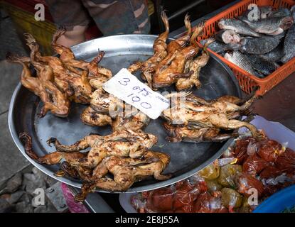 From above of exotic fried frogs on tray placed on stall of local street food market with assorted fish and spices in Thailand Stock Photo