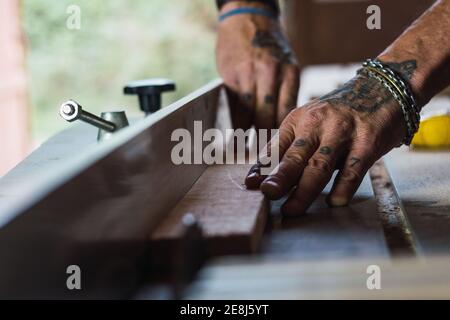 Closeup of crop unrecognizable male without a thumb joiner cutting wood with circular saw in joinery Stock Photo