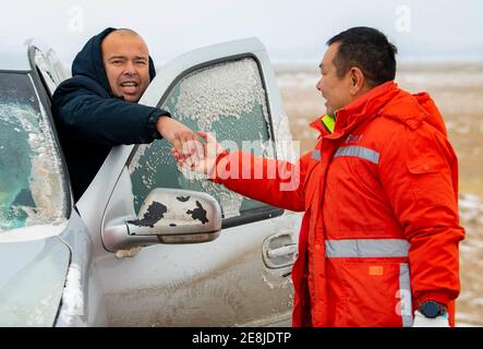 (210131) -- URUMQI, Jan. 31, 2021 (Xinhua) -- A staff member of the Maytas wind prevention and rescuing base is thanked by a driver who has been rescued in Maytas, Emin County of northwest China's Xinjiang Uygur Autonomous Region, Jan. 24, 2021. Maytas, located in Emin County, is an important thoroughfare with tough weather conditions of snowstorms and heavy wind for about half a year.   Since 2002, the Maytas wind prevention and rescuing base has been responsible for road clearing and rescuing of the S201 in the region. For people who are on duty here, work can last day and night. They patrol Stock Photo