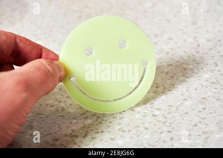 Man's hand holding an International day of happiness, plastic smiling face toy. Happiness and joy concepts Stock Photo