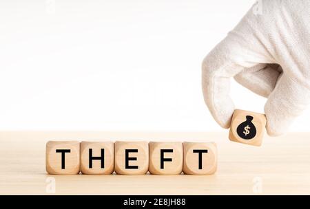 Theft concept. Hand picking a wooden block whit money bag icon and text on wooden dice. Copy space. White background Stock Photo