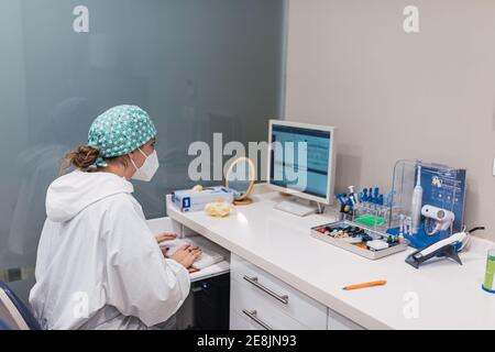 Female dentist using computer at office desk. Looking at the screen Stock Photo