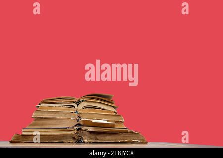 there are many old open books with bookmarks on wooden table on red background Stock Photo
