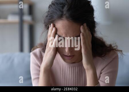 Unhealthy frowning young woman suffering from headache. Stock Photo