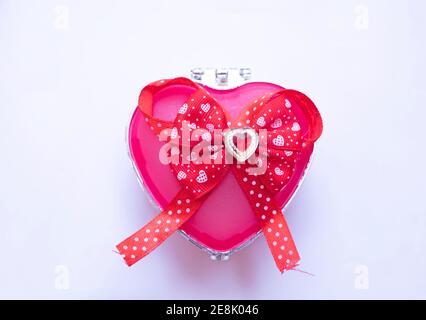 Pink gift box heart shape and a red bow with a red stone on white background, gift concept Valentine's day, Stock Photo