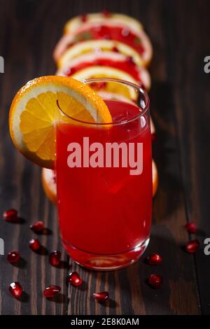 Fresh juice from grapefruits and pomegranates on a dark, wooden background. Stock Photo