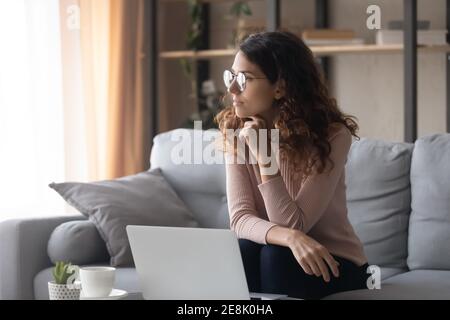 Distracted from online computer work young woman looking in distance. Stock Photo