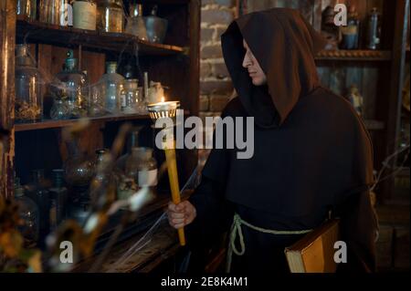 Male exorcist in black hood holding a torch Stock Photo