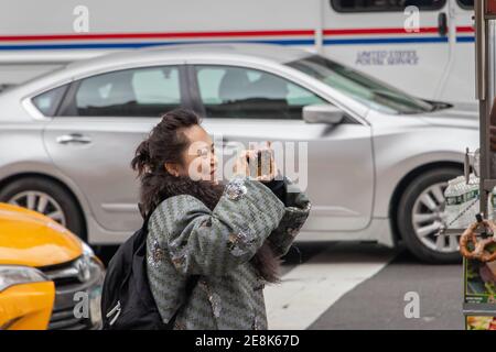 middle aged asian woman tourist possibly Chinese taking photograph on new York street Stock Photo