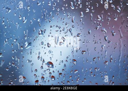 rain droplets on glass over calm colorful background. Stock Photo