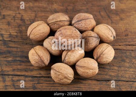 group of fresh raw walnuts on old wooden board background. rustic and detailed image Stock Photo