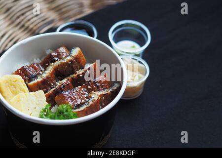 Top view and focus to Unadon or unagi donburi or eel bowl is a dish originating in Japan on black background. Stock Photo