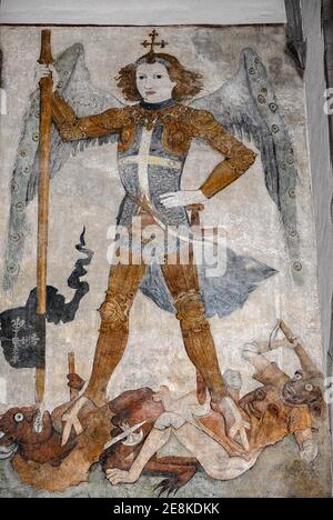 St Michael the Archangel, triumphant, crushes two demons underfoot while lancing one through the mouth.  Late Gothic 1400s fresco, attributed to German artist Jost Haller, in the Église Saint-Thomas Lutheran church in Strasbourg, Bas-Rhin, Alsace, Grand-Est, France. Stock Photo