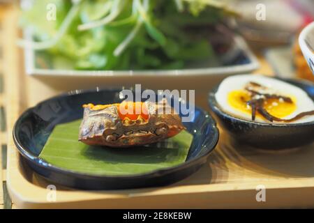 Crab eggs in Crab shell on banana leaf with half boiled egg on a table - Breakfast set Japanese style Stock Photo