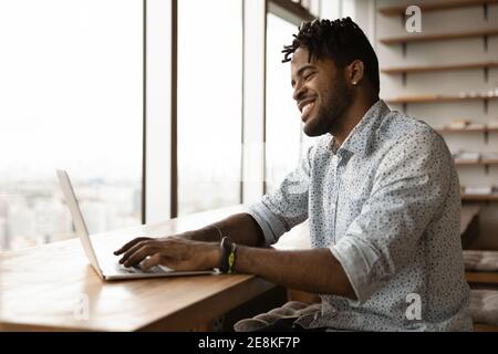 Happy young afro man playing pc video game on laptop Stock Photo