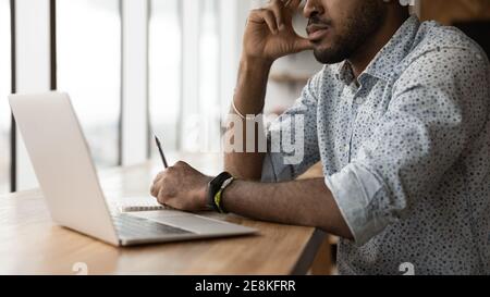 Pensive young black man sit at desk before pc screen Stock Photo
