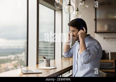 Motivated male student putting headphones on learning foreign language online Stock Photo