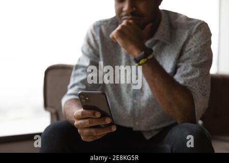 Cropped shot of thoughtful african guy reading email on cell Stock Photo
