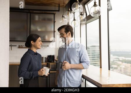 Happy mixed race couple drink tea coffee by picture window Stock Photo