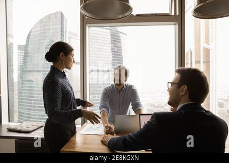 Young men sitting by laptops listening to indian lady ceo Stock Photo