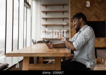 Young african male point finger on cell screen making choice Stock Photo