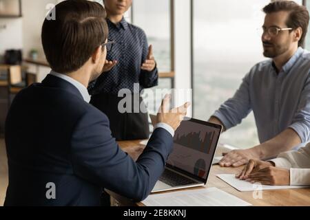 Diverse business team discuss statistical report infographics charts using laptop Stock Photo