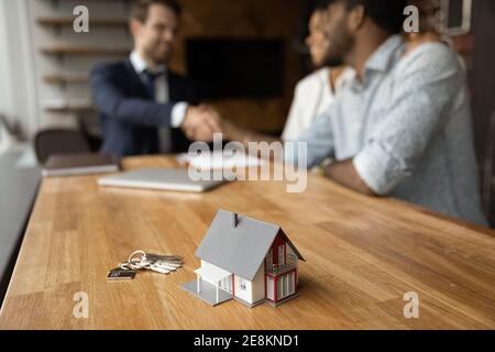 Closeup of keys and toy cottage house on wooden table Stock Photo