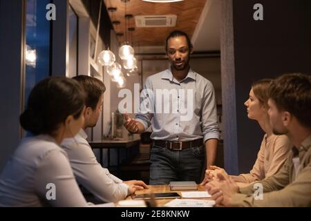 Enthusiastic young african guy present problem solution to diverse colleagues Stock Photo