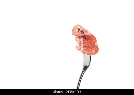 Two thin slices of cooked smoked sausage on a fork. Sausage on a fork over white background with place for text. Close up. Stock Photo
