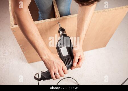 A man drills a hole in a closet. Stock Photo