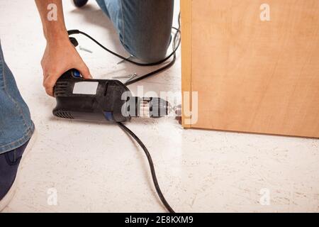 A man drills a hole in the corner of the closet. Stock Photo