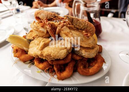 Closeup of a serving dish filled with a mixed deep-fried fish in a restaurant on the Barcelona seafront, Catalonia, Spain, Europe. Stock Photo