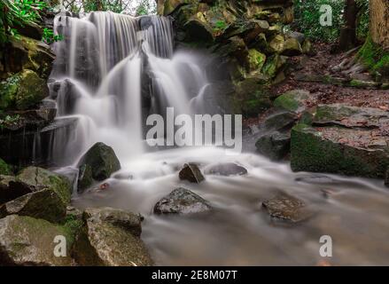 Chorlton Brook cascading over the rocks of the waterfall after heavy rain at Abney Hall Park, Cheadle, Stockport, Greater Manchester Stock Photo