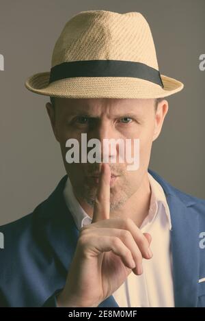 Face of mature businessman with finger on lips Stock Photo