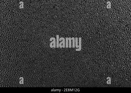 Rough black plastic finish microstructure with micro bubbles surface texture and flat and even background. Abstract dark background. Stock Photo