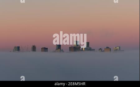 City in the clouds, Paradise city, City of Angels, Vancouver City Skyscrapers over the fog with the morning sun who create a reflective false sunset Stock Photo
