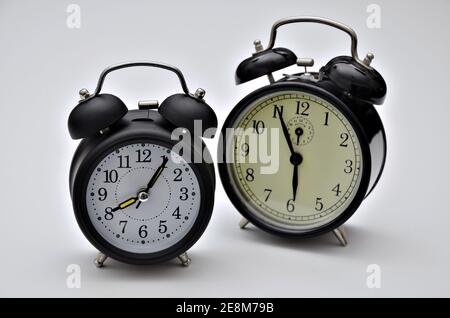 close up of two black retro  alarm clocks with twin bells, showing different times Stock Photo