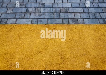 Playground with yellow rubber surface coating and grey tiles Stock Photo